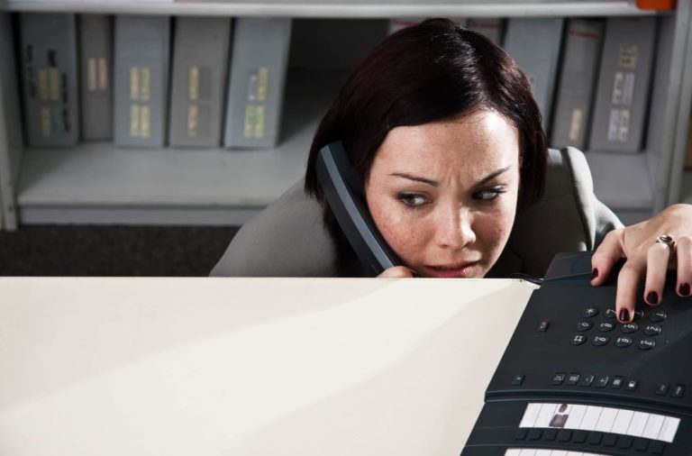 Scared Woman Hiding in Office on Phone