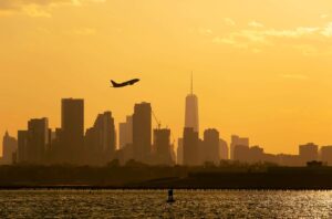 Airplane Over New York City Skyline at Sunset